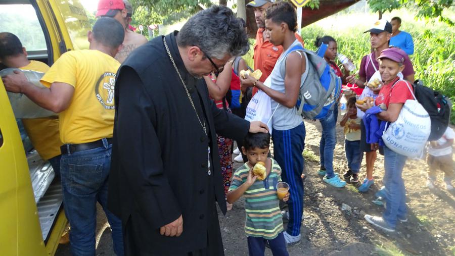 Working together, Greek Orthodox and Roman Catholic priests and Volunteer Ministers deliver food to refugees on the Colombian border.