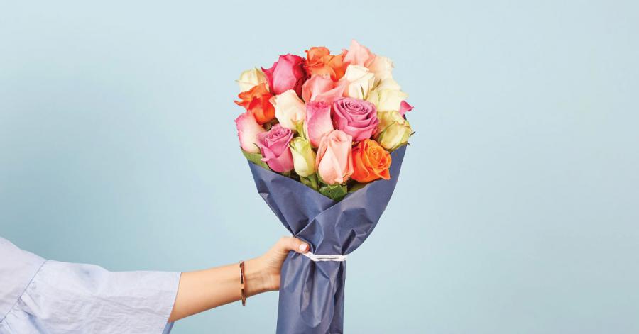 Handing bouquet of multi-color roses on blue backdrop.