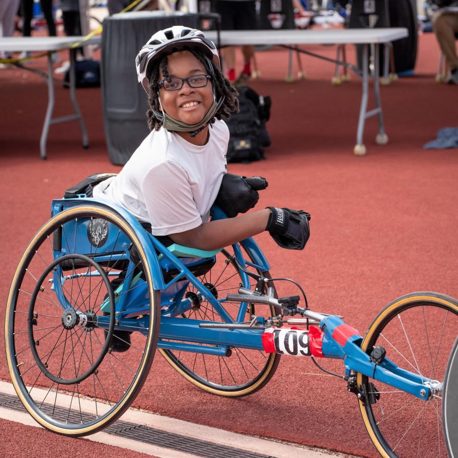 A young black athlete in her racing wheelchair on the track