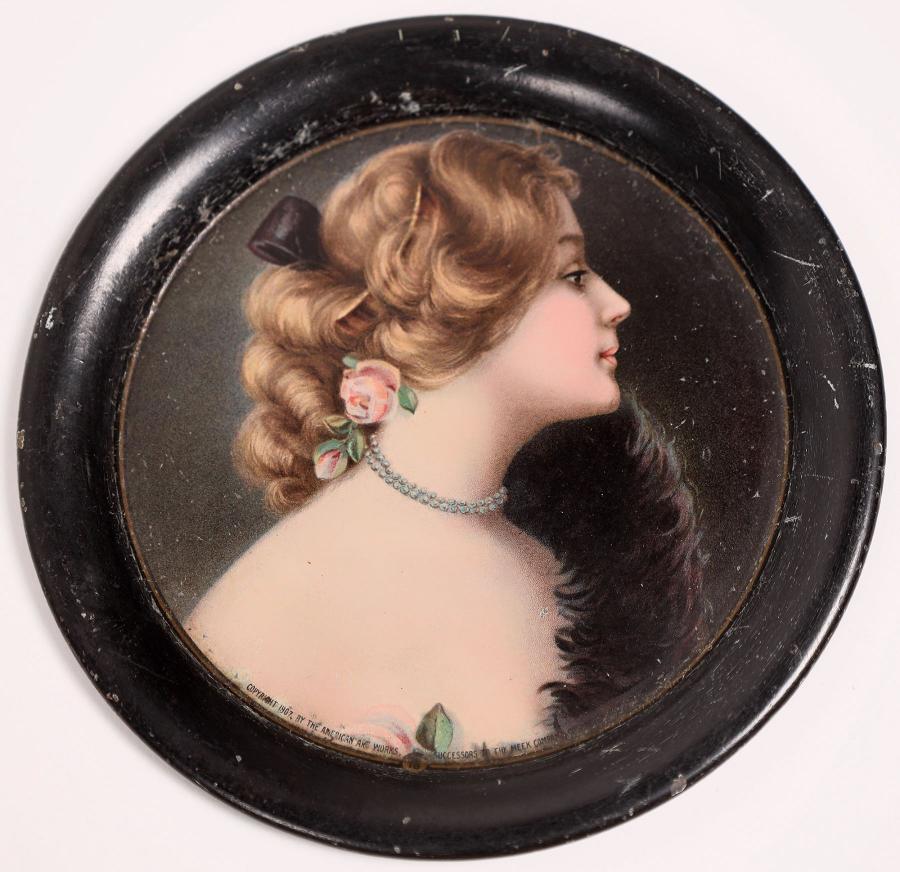 Vintage metal tip tray, late 19th century, circular, 4 ¼ inches in diameter, with an image of a young woman with flower earrings (est. $100-$150).