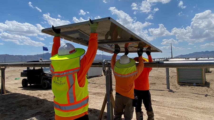 Rosendin employees carry a solar panel for installation at a facility in California