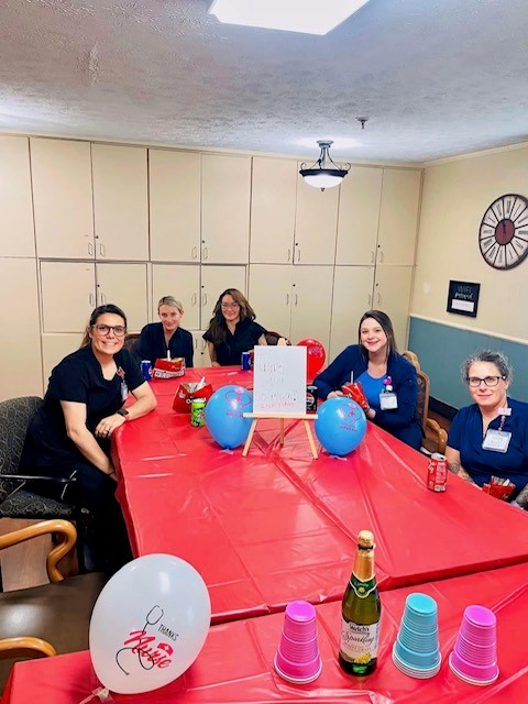 Nurses at Madison Health & Rehab sitting around a table celebrating the landmark achievement.