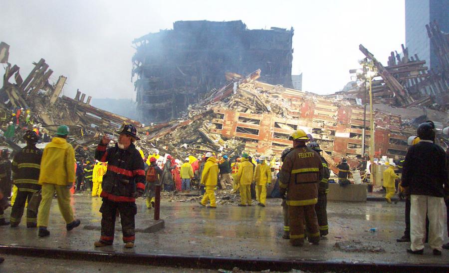 FDNY first responders stand in front of smoldering rubble at Ground Zero on 9/11.