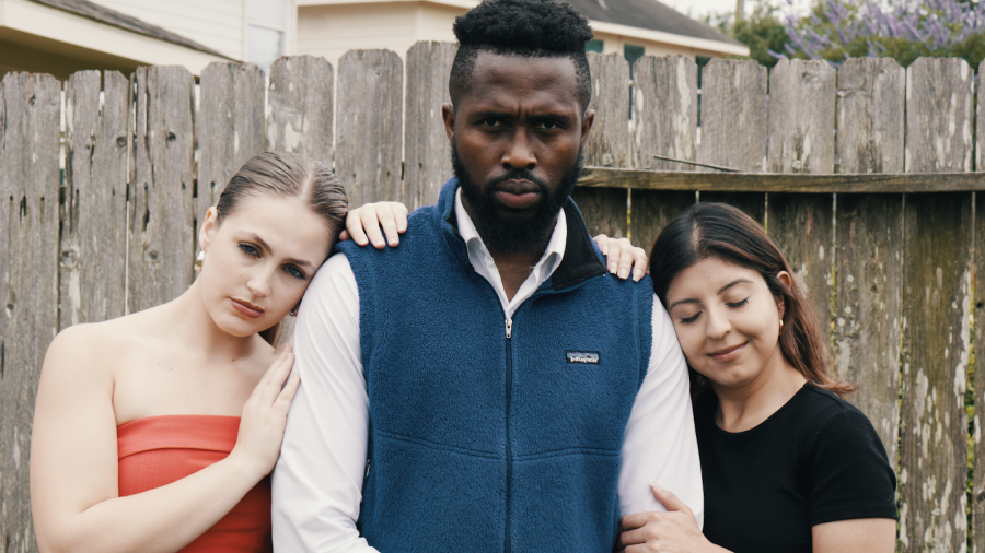 Mr. FoW stands in the center, with two women resting their heads on his shoulders, capturing a moment of tenderness and connection.