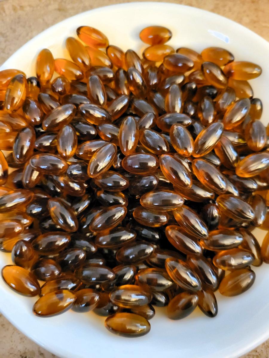 a plate of hundreds of gelcaps, overhead shot, brown and amber colors, on a white plate