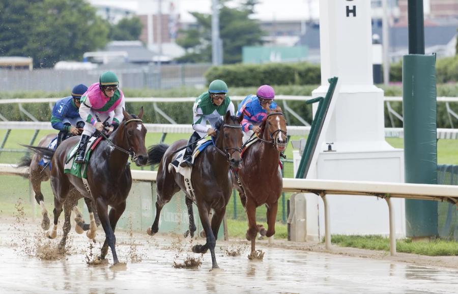 A horserace in progress on a muddy racetrack