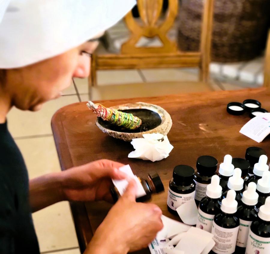 just the face and hands of a sister working at a table labeling jars