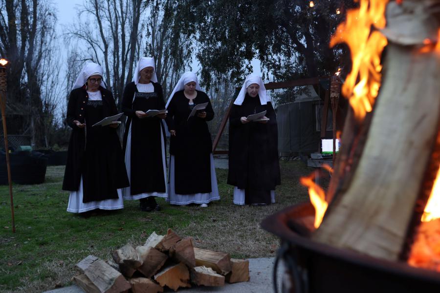 a fire in the forefront, with the Sisters in veil in the background