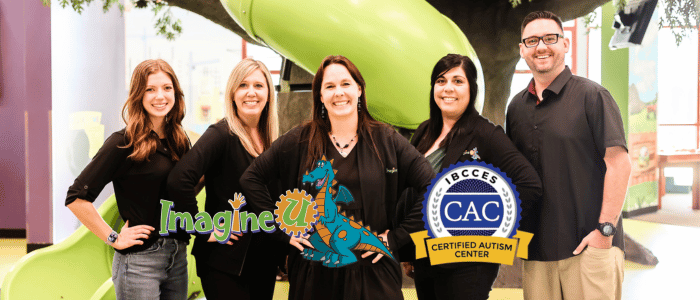 A group of five people posing in front of a green slide, with the ImagineU logo and the IBCCES Certified Autism Center™ badge displayed in the foreground.