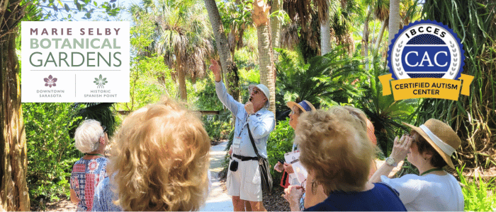 A tour guide gesturing upward to a group of visitors at Marie Selby Botanical Gardens.