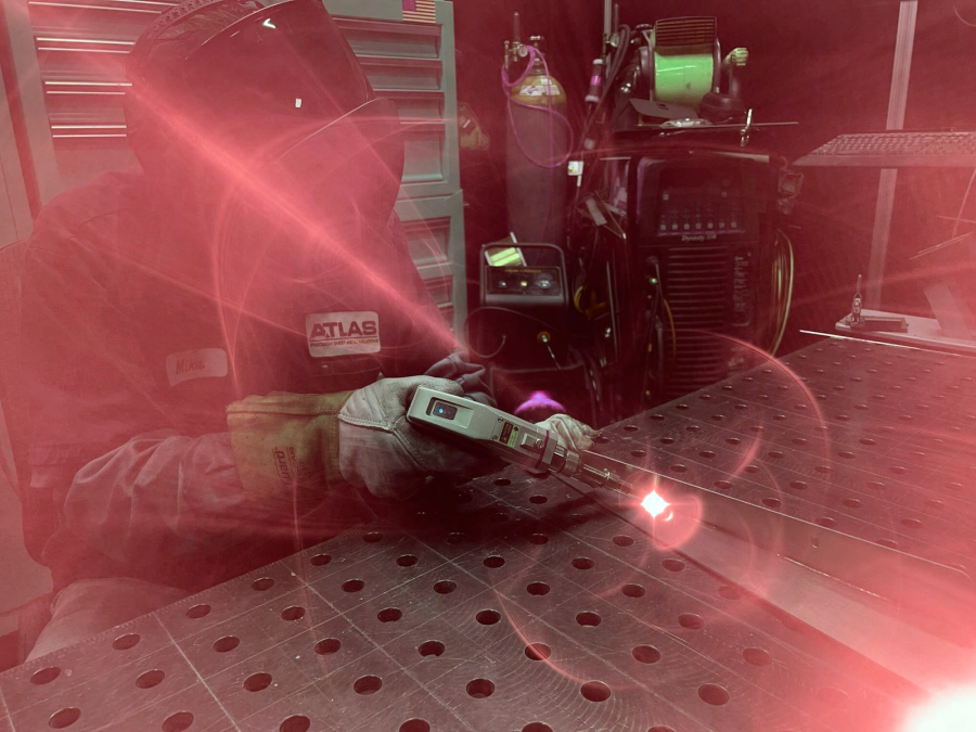 A technician at Atlas Manufacturing uses advanced laser welding equipment to weld a sheet metal component, showcasing precision and cutting-edge fabrication capabilities.