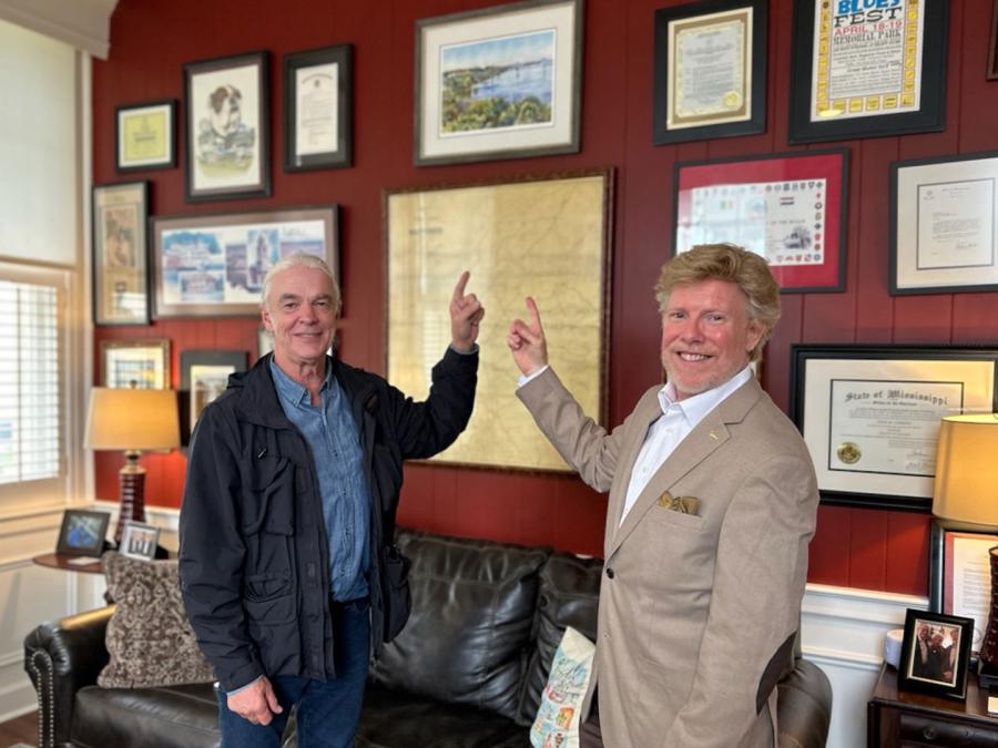 Artist Wyatt Waters and Natchez Mayor Dan Gibson in his office, pointing to a framed giclee print of Wyatt's watercolor painting of the bridge over the Mississippi River Bluff.