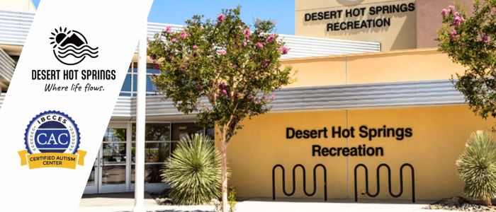 Exterior view of Desert Hot Springs Recreation Center, featuring trees, signage, and a certification badge for autism services.