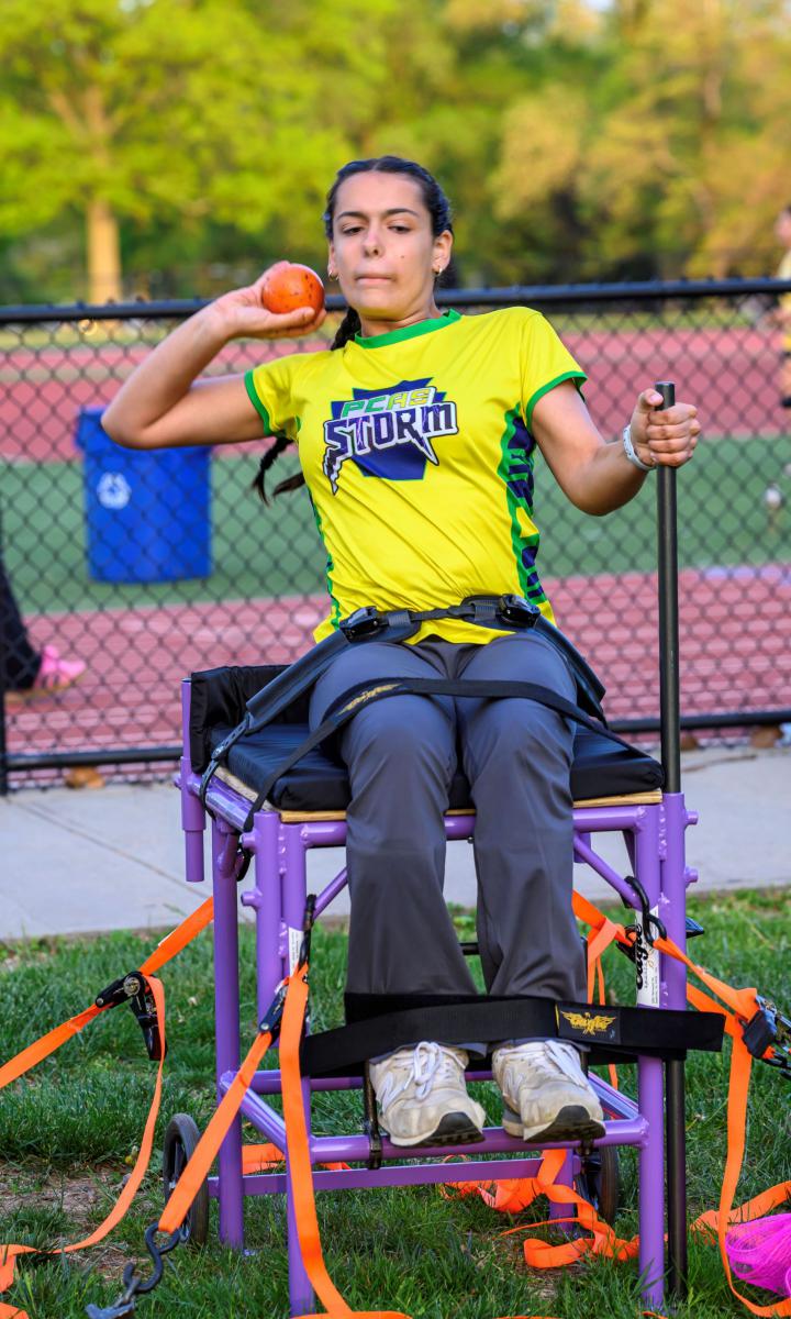 Sabrina throwing a shotput from her adaptive field chair