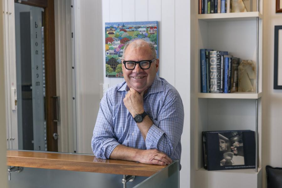 Dion Seminara smiling leaning against reception desk inside dion seminara architecture’s Brisbane studio, offering personalised SHAPE Design Consultations.