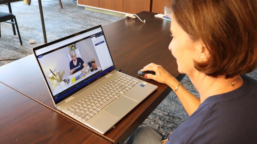 Judy, an woman over 60 is on her laptop using it to watch an art class on GetSetUp and explore virtual health and wellness classes to help her live healthier and happier.