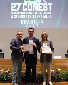 Rony Jabour holding a certificate alongside Benvenuto Gonçalves, President of the Lusophone Association of Engineering, Occupational Safety and Environmental Health, and Larissa Barreto, President of ABRAEST, Events Director at ANEST, and Organizer of the