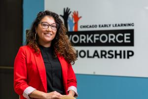 Sandy De León poses in front of the Chicago Early Learning Workforce Scholarship sign at Truman College