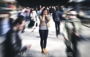 Woman covering her face while experiencing anxiety or panic symptoms in a crowded public setting.