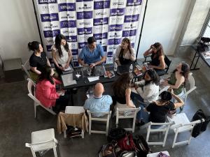 Aspiring models and actors seated in a circle around a table engage in direct portfolio reviews with industry professionals at a VIP Ignite Miami networking event, with a branded step-and-repeat banner displaying the VIP Ignite, Truth Management, and The