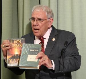 Chairman and historian of the L. Ron Hubbard Foundation Mr. Bill Runyon holds up an original copy of Dianetics: The Modern Science of Mental Health from 1950, along with the more familiar – and more colorful -  current edition.