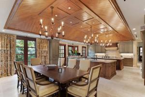 The gourmet kitchen features two islands, a stunning vaulted wood ceiling, and chandeliers.