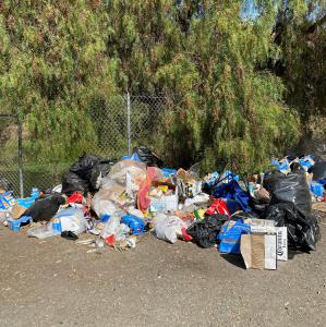 A large amount of trash is located next to a fence.
