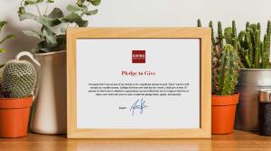 A physical framed Giving What We Can Pledge certificate on a shelf