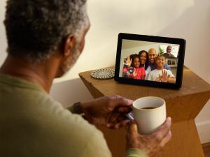 Black senior citizen watches screen as he video chats with family.