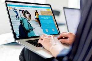A man is browsing the www.EMMAnotify.com website on his laptop.