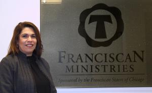Photo of Monica Simzyk, the Chief People Officer for Franciscan Ministries, standing in Ministry Office in front of