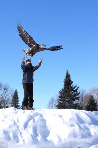 Wings of Wonder Founder Rebecca Lessard releases Bald Eagle into the blue sky at the top of a snowy hill in Michigan