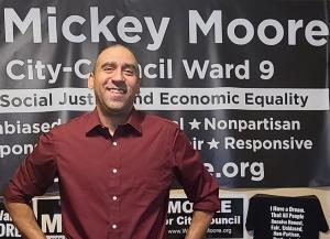 Candidate Mickey Moore standing in front of campaign banners