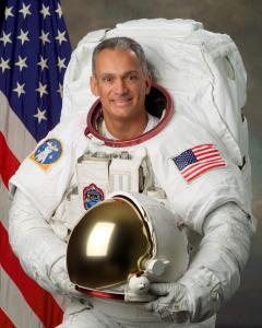 The official Astronaut portrait of Astronaut John "Danny" Olivas in his EVA (aka Spaceswalk) white suit holding his helmet (Photo Credit NASA)