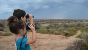 Two children birdwatching with binoculars.