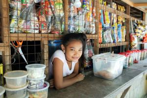 Young female from Phillipine stands content at a counter, showcasing how FundLife protects young girls through non-formal education!