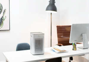 An photograph of a Medify Air purifier sitting next to a computer on a desk in an office.