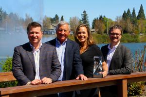 Alex Casebeer, Scott Casebeer, Diana Davis (General Manager, Toyota Portland Region) and Matthew Casebeer standing outside on a bridge with the 50th Anniversary Award from Toyota