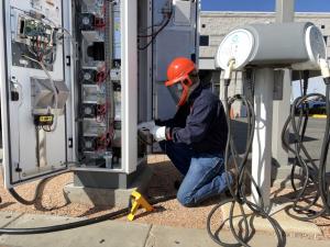 An In-Charge Energy field technician works on an EV charger at a fleet site.