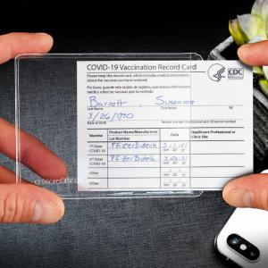 A vaccination card being slipped into a clear plastic pocket.