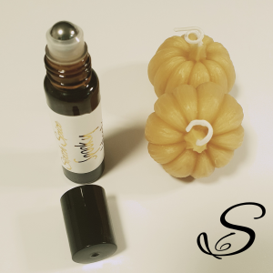 This photo shows the brown amber bottle standing upright with its black plastic cap taken off of it.  The cap is in front of the bottle and the stainless steel roller is being shown.  This is to show people that the natural perfumes are applied using a gl