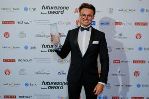 Philipp Efferl at the futurezone Awards in Vienna with the Award. He holds the award and smiles to the photographers.