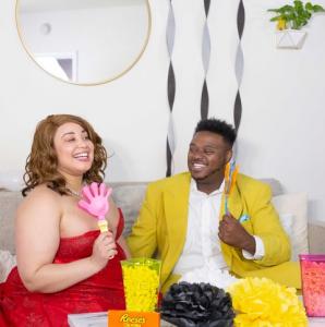 Models Crystal Renee and Lance Franklin II prepare for their Full Figured Industry Awards watch party.  Both models are dressed in evening attire, sitting on a couch.