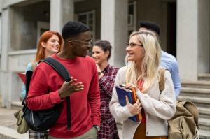 Five university students holding books and school backpack while talking together