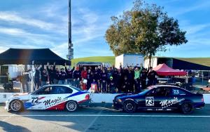 MooreWood Creative race team crew stands behind their #72 white racecar and #73 black race car at Thunderhill Raceway