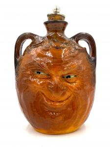 Double-handled bottle by RW Martin and Brothers (British, 1873-1914), made in 1901, depicting a smiling figure's face ($12,300).