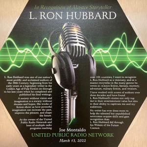 Plaque recognizing L. Ron Hubbard as a master storyteller on his birthday, March 13, 2022,presented by Joe Montaldo, CEO United Public Radio Network