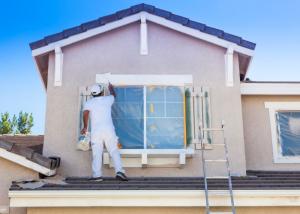 worker completing exterior house painting in Minneapolis MN