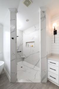 Bathroom tub to shower conversion featuring Statuario engineered stone.