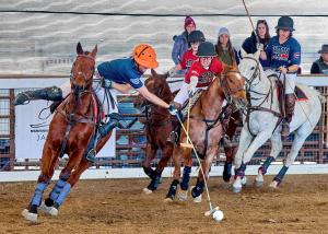 Arena Polo action on horses with a James Glew hitting the ball while Mark Osburn reaches to hook his mallet